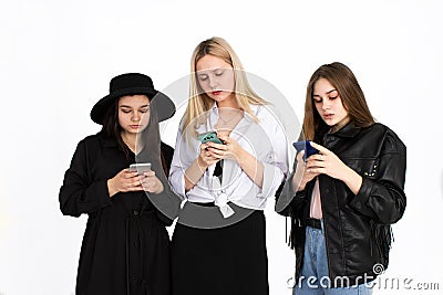 Three young beautiful girls are looking at their smartphones Stock Photo