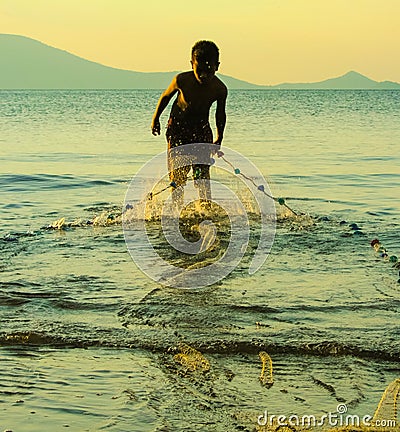 Child Worker, with fishing net pulling in the days catch, Editorial Stock Photo