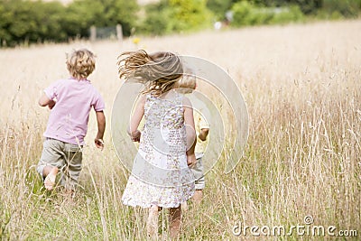 Three young children running outdoors Stock Photo