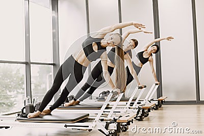 Three girls in a bright gym synchronously stretching with equipment Stock Photo