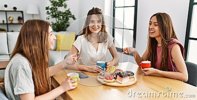 Three young friends woman smiling happy having breakfast sitting on the table at home Stock Photo