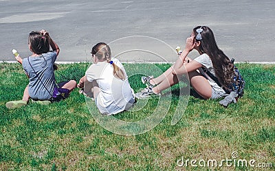 Three young girls sitting in grass, rear view Stock Photo