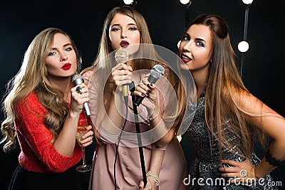 Three young smiley beautiful women in karaoke Stock Photo