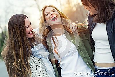 Three young women talking and laughing in the street. Stock Photo