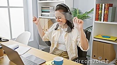 Thrilling sight of a young, radiant, hispanic woman, an adept business worker, delightfully swaying to the rhythm of music via Stock Photo