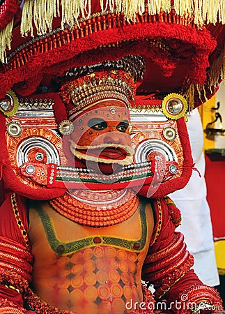 A Theyyam artist is adorned with traditional colorful costume before a performance at the festival in Kannur, Kerala, India. Editorial Stock Photo