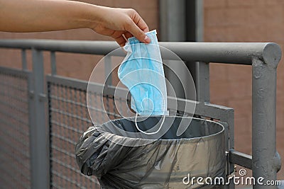 Throw surgical mask in public garbage can in city street. Hygienic mask puts in the trash Stock Photo