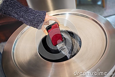 Throwing away mobile phone into rubbish bin. Stock Photo