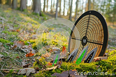 Throwing knives and a round target for throwing in a forest.Sport and hobby. metal knives for throwing.Outdoor sports Stock Photo