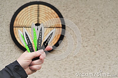 Throwing knives. Sport and hobby . Throwing knives in a man& x27;s hand close-up and a target on the wall.Outdoor sports Stock Photo