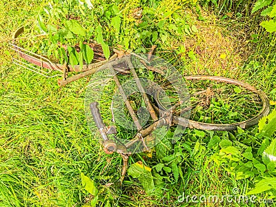 Thrown away old rusty bike in the park on a grass field Stock Photo