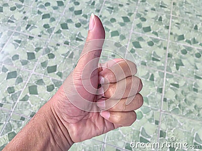 Thumb hand sign on blurred tile green background, agree thumb sign, hand up okay symbol, thumb up for agreement or ok gesture sign Stock Photo