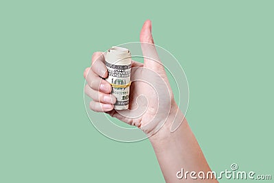 Thumbs up with roll of money isolated on green background Stock Photo