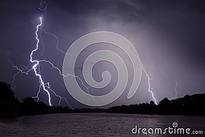 Thunder, lightnings and rain during storm over river and forest Stock Photo