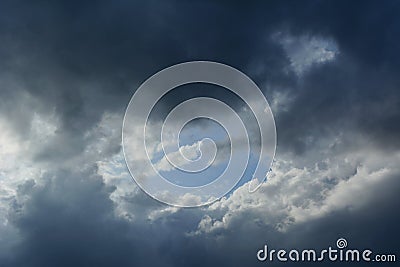 Thunder Sky. Dramatic cloudscape with blue sky in the center, surrounded by grey clouds Stock Photo