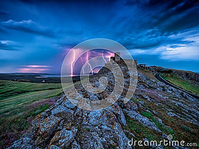 Thunderbolts lightning on a cloudy evening blue sky over old Enisala stronghold citadel Stock Photo