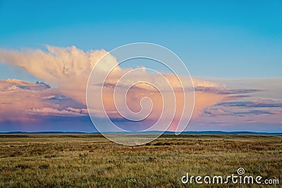 Thundercloud at sunset with streams of rain and a rainbow from the sun Stock Photo