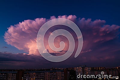 Thunderstorm in shape of explosion over the city on a warm summer evening. Cumulonimbus Incus cloud in a shape of nuclear mushroom Stock Photo