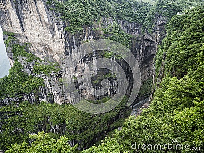 The Tianmen Mountain with a view of the cave Known as The Heaven`s Gate surrounded by the green forest and mist at Zhangjiagie, H Stock Photo