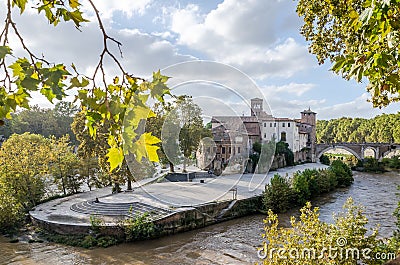 Tiberina Island, surrounded by vegetation and trees washed by water of the Tiber River in the capital of Italy, Rome Stock Photo