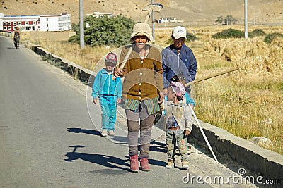 CLOSE UP: Two adult women carrying shovels walk down the road with little kids. Editorial Stock Photo