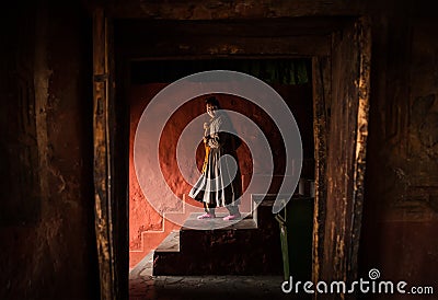 Tibetan monk woman goes down the stairs in Thiksey Monastery Editorial Stock Photo