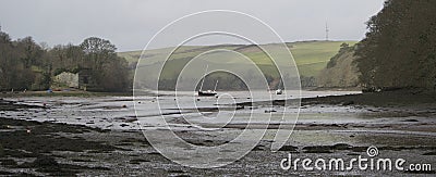 Tidal estuary at low tide: boats moored at anchor; mud; ruined lime kiln buildings Stock Photo