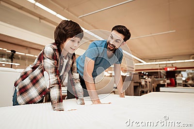 Tidy bearded father with young son is testing mattress for softness. Stock Photo