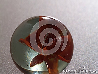 Tight Shot Of A Single Marble On Gray Surface Stock Photo