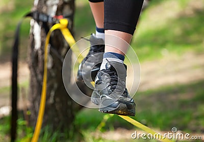 Tightrope walker is on a tight sling, which is fixed on the trees, at a low altitude. Stock Photo