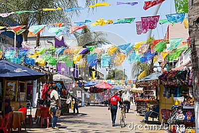 People Shop Beneath Hanging Flags in Tijuana, Mexico Editorial Stock Photo