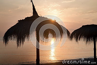 Tiki hut umbrellas, thatch. Sunrise, sunset view on beach in Tunisia Stock Photo