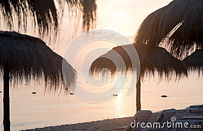 Tiki hut umbrellas, thatch. Sunrise view on beach in Tunisia. Travel Stock Photo