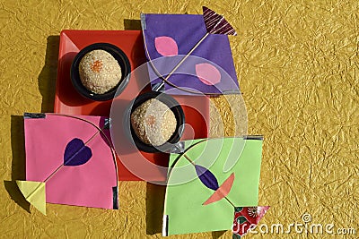 Til ka Laddoo made of Sesame seeds and jaggery or sugar, also known as Til baati. Sankranti food celebration with kites. Yellow Stock Photo