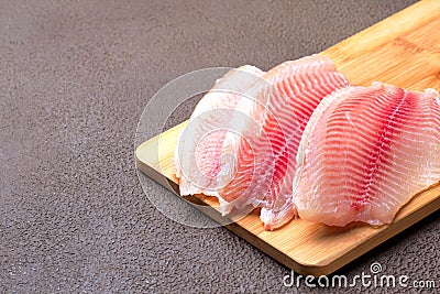 Tilapia fillet with lemon, rosemary and lettuce on a cutting board Stock Photo