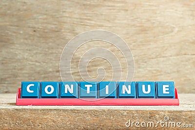 Tile letter on rack in word continue on wood background Stock Photo