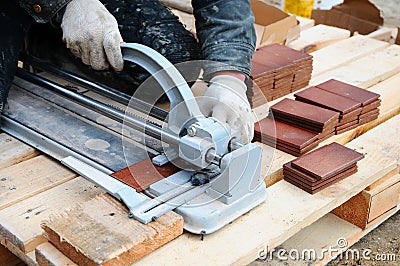 Tiler construction worker cuts tiles Tile. Working with decorative tile cutting equipment at repair renovation work Stock Photo