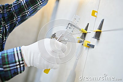 Tiler installing large format tile on wall. tile leveling system Stock Photo