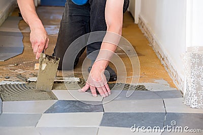 Tiler laying floor tiles on adhesive Stock Photo