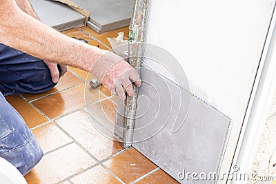 The tiler lays a ceramic tile on the wall Stock Photo