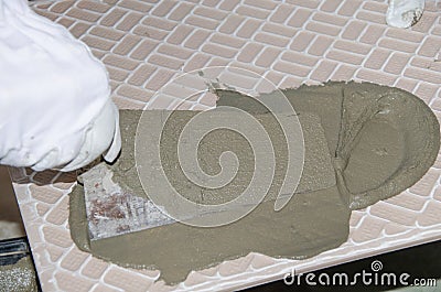 Tiler spreading tile adhesive on the back of a tile Stock Photo