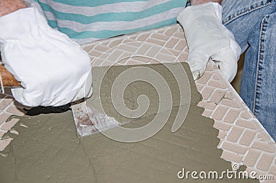 Tiler spreading tile adhesive on the back of a tile Stock Photo