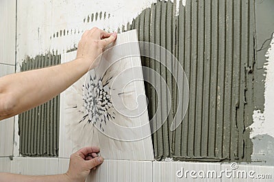Tilers hands are installing a ceramic tile. Stock Photo