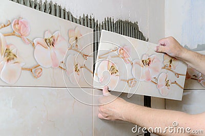 Tilers hands are installing a ceramic tile. Stock Photo