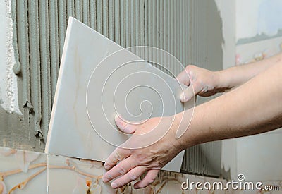 Tilers hands are installing a ceramic tile. Stock Photo