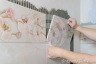 Tilers hands are installing a ceramic tile. Stock Photo