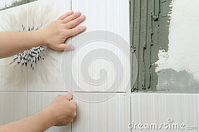 Tilers hands are installing a ceramic tile. Stock Photo