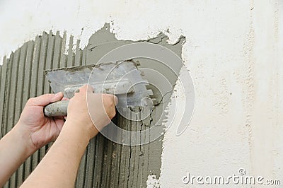 Tilers hands are putting an adhesive. Stock Photo
