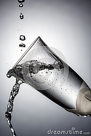 Tilted champagne glass close-up with frozen water jets and splashes in white backlight. Stop motion photography Stock Photo