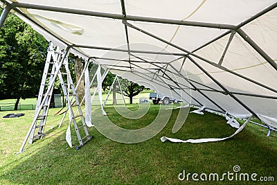 Tilted event tent during set up and ladders on the lawn in a park for a summer party or wedding Stock Photo